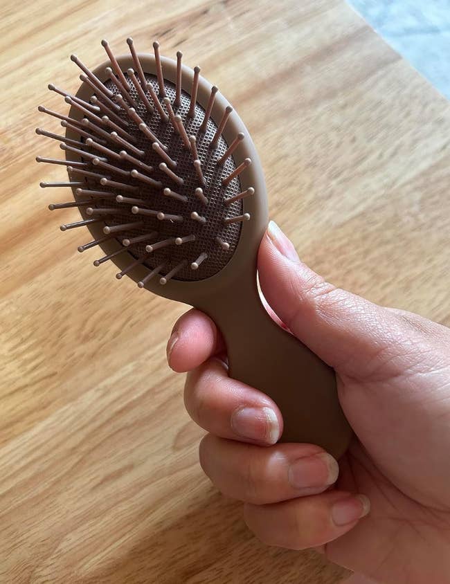 A tiny bristled mocha colored hairbrush