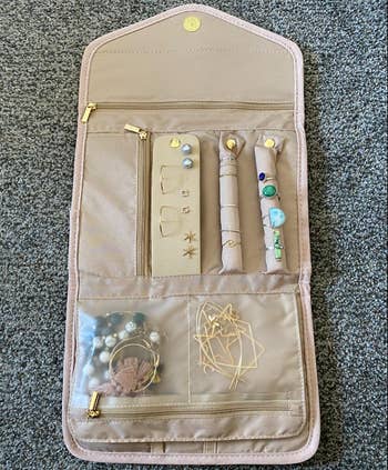 reviewer photo of the jewelry organizer's interior, which has sections for earrings and rings along with several pockets