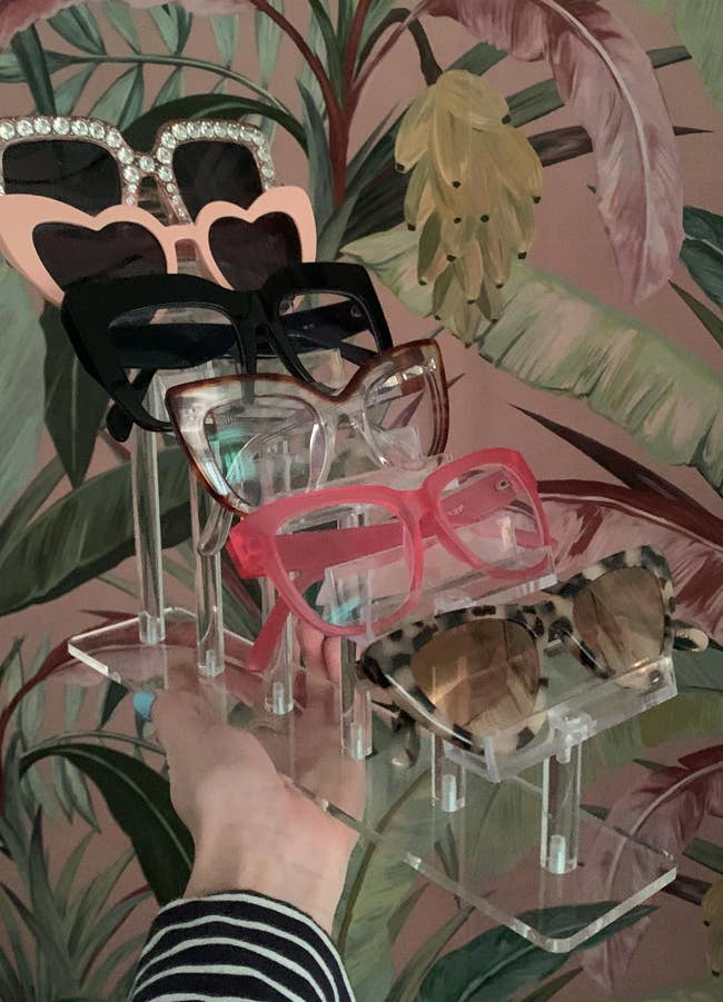 A manus displays a assortment of stylish sunglasses connected a stand