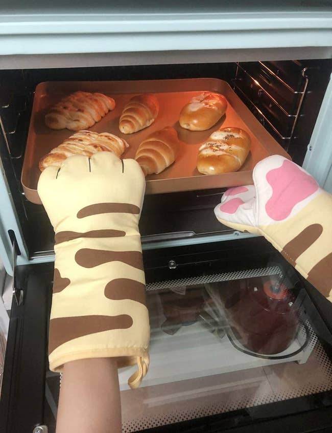 model wearing the cat paw like mitts when pulling a cookie sheet out of the oven