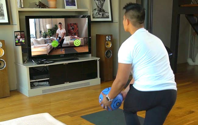 person using smart ball in living room with themselves on the screen to show where they should move the ball