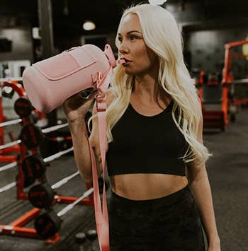model drinking from water bottle at gym