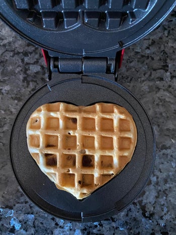 Reviewer's waffle maker with a heart shaped waffle in it being cooked