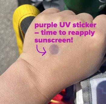 A reviewer's child wearing a UV sticker that has turned purple, labeled 