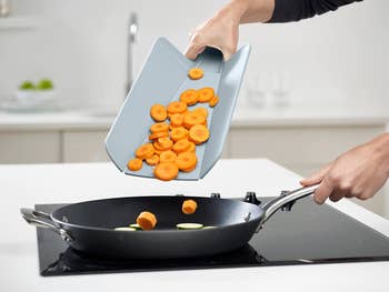 person pouring the carrots into a pan