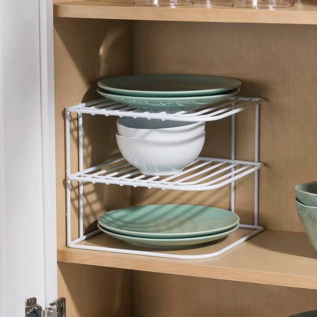 Wire shelf in cabinet holds plates and bowls for organized storage, enhancing kitchen space efficiency