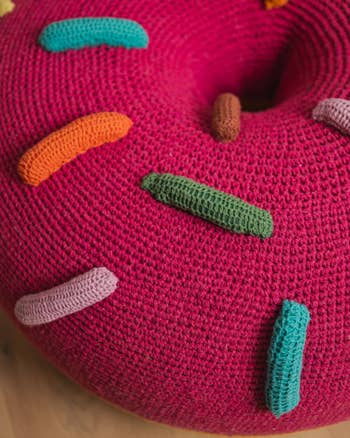 Close-up of a hand-crafted crochet donut cushion with various colored stitches as sprinkles