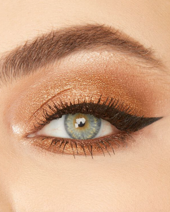 a model's eye with winged liner and shimmery gold eye shadow 