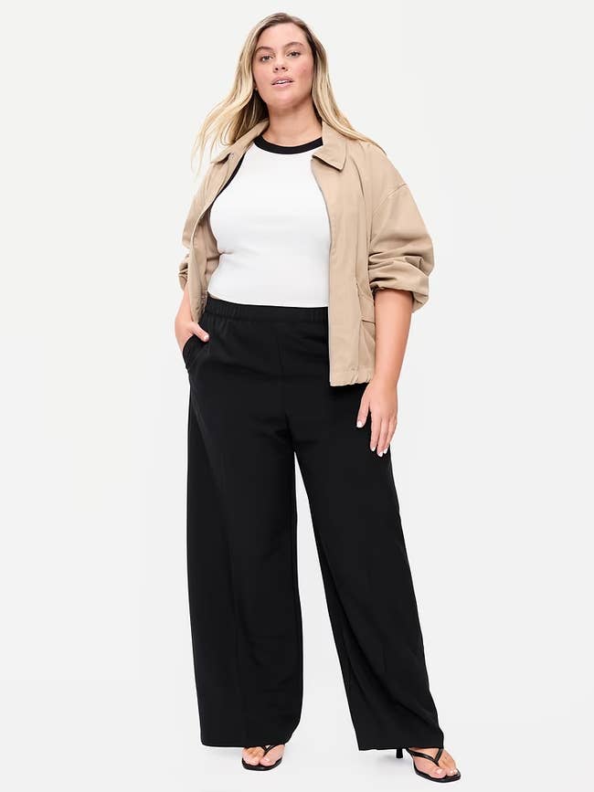 Person poses successful  a casual outfit with a beige jacket, achromatic  top, achromatic  wide-leg pants, and heels, suitable for a stylish yet relaxed look