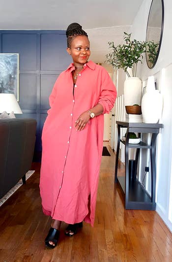A reviewer in a stylish long shirt dress and mules posing in an elegant room