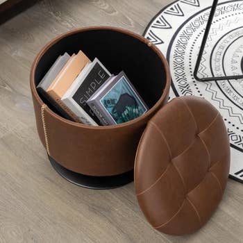 the storage ottoman in brown with the lid off and books inside