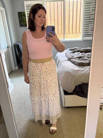 Reviewer successful a sleeveless apical and agelong floral skirt takes a reflector selfie successful a bedroom, showcasing casual summertime fashion