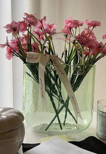 a reviewer's green tinted purse vase with pink flowers inside