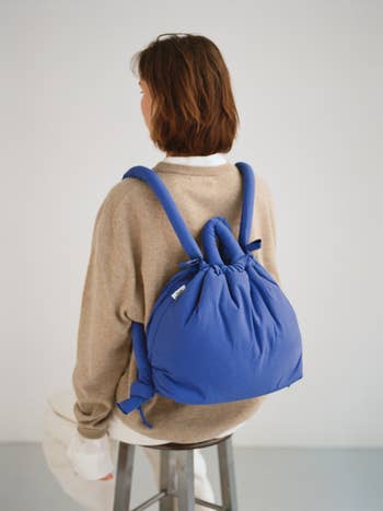 a model wearing the cobalt blue multi-use bag as a backpack