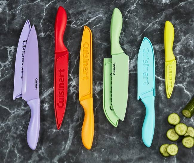 colorful knife set on a counter next to sliced up cucumber