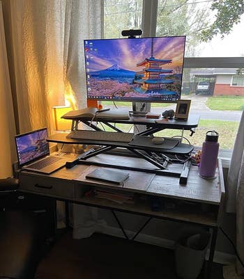 Home office setup with a laptop on top of a sit-to-stand converter