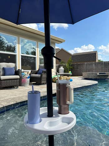 Poolside umbrella stand with attached tray holding two tumblers