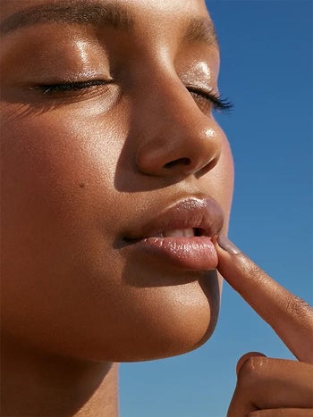 model applying the balm to their lips with their finger
