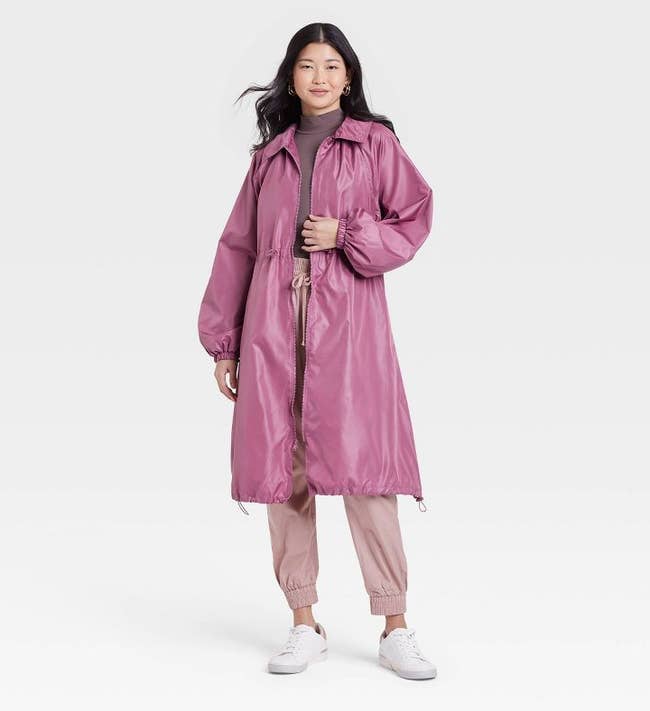 model wearing a long pink raincoat