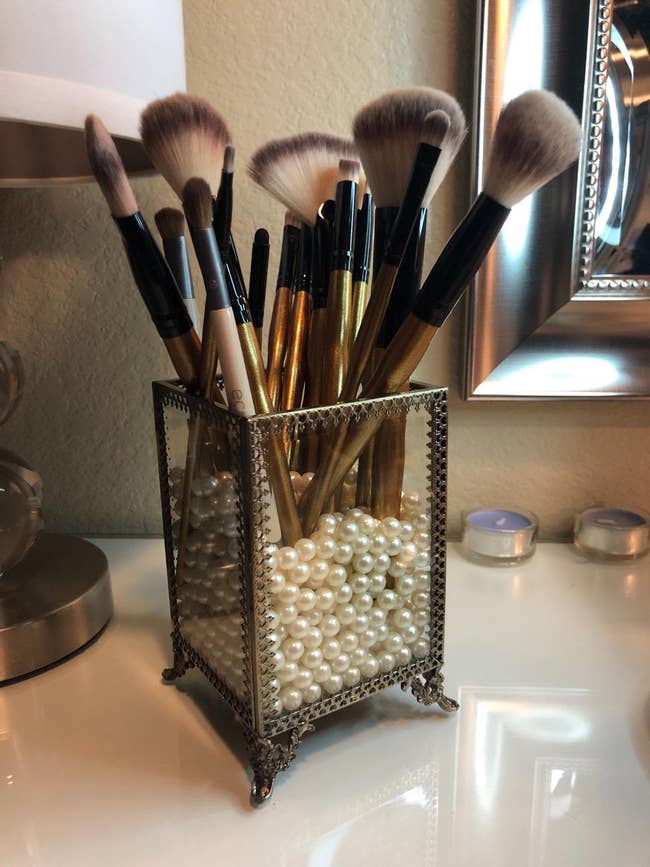 reviewer's holder filled with white pearl beads with makeup brushes in it