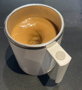 A reviewer's white mug with coffee swirling in it 