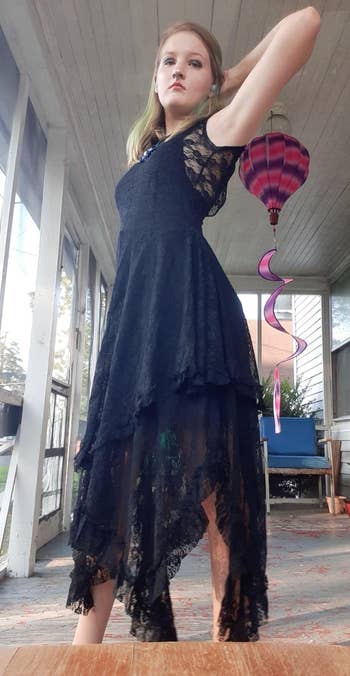 Reviewer in asymmetrical lace dress posing confidently on a porch