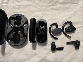 Various wireless earbuds and their cases displayed on a surface, showcasing different designs and styles for a shopping article