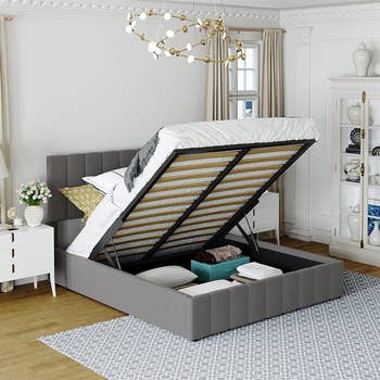 the grey upholstered bed lifted up to show the storage underneath