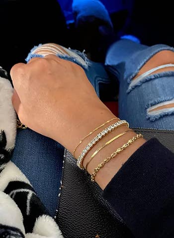 the tennis bracelet layered with other bracelets on a reviewer's arm