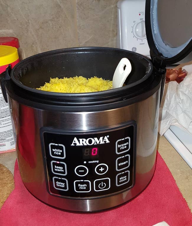 a reviewer. photo of an open rice cooker filled with yellow rice 