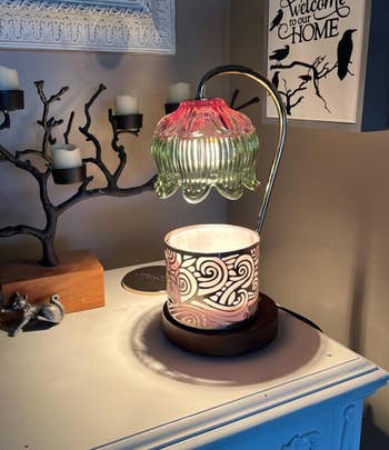 green and pink warmer lamp with a candle placed under it