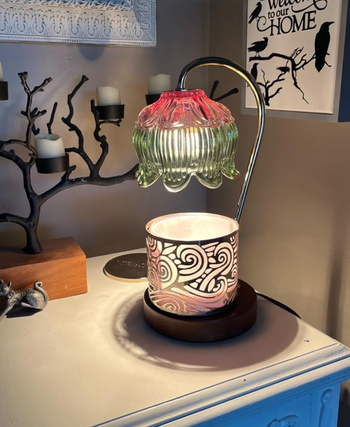 green and pink warmer lamp with a candle placed under it