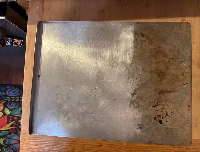 A well-used, half-discolored metallic  baking expanse  connected  a woody  counter