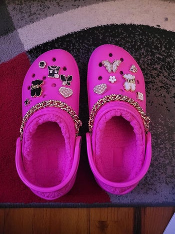 reviewer's pink fleece lined crocs with Jibbitz on them