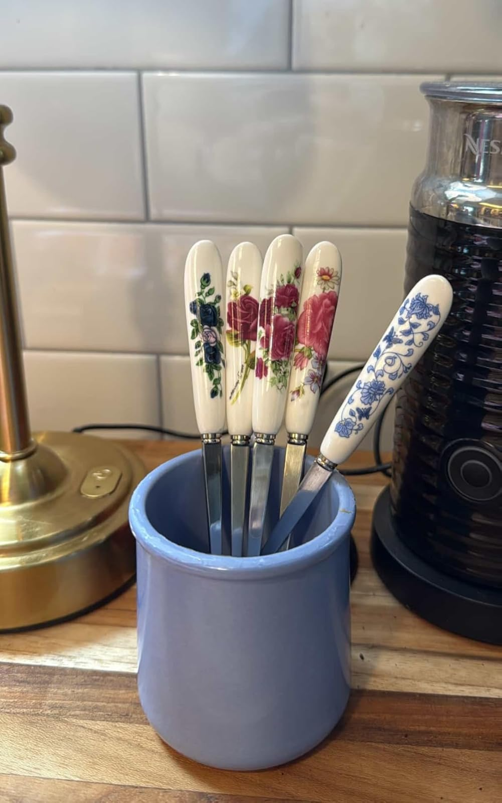 Five floral-patterned food  knives with ceramic handles basal   successful  a bluish  holder connected  a room  counter
