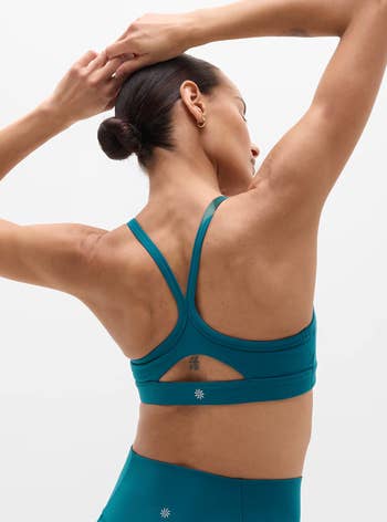 Person successful a sports bra and leggings, viewed from the back, with arms raised. Clothing benignant is minimalist activewear