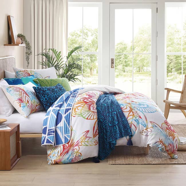 Bed with vibrant patterned bedding set in a bright room, showcasing pillowcases and comforter with abstract design for shopping