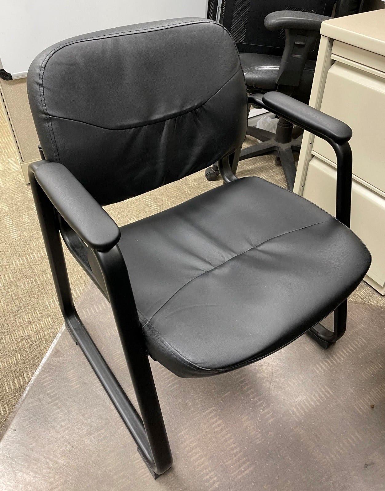 Reviewer image of black leather chair with sled bottom on top of carpet 