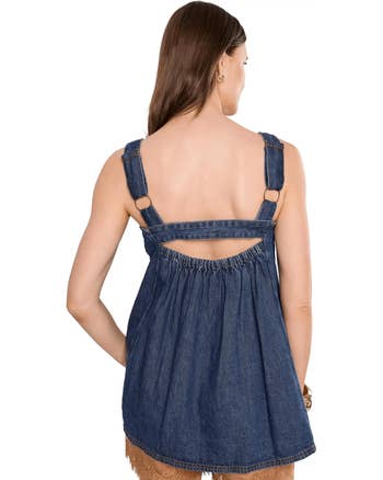 Woman wearing a denim sleeveless apical with ringing details and a gathered back, showing the garment's benignant and acceptable from the back