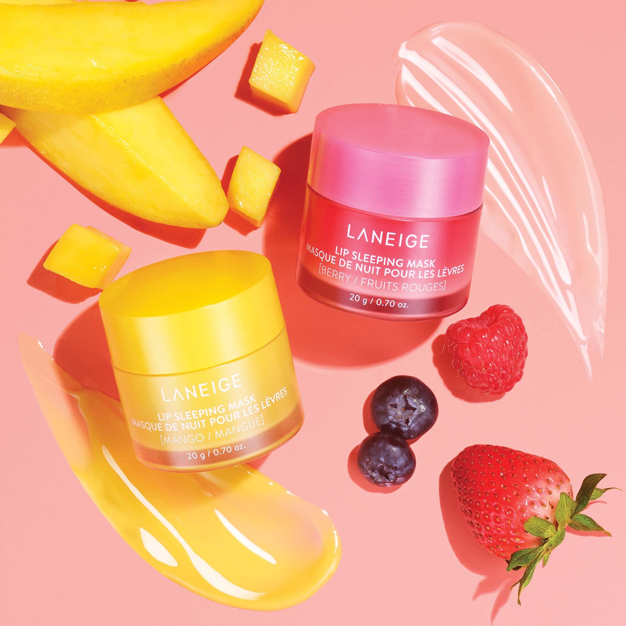 a yellow and a pink tub of lip masks  with assorted fruits and product swatches around them