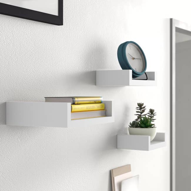 A set of three different sized white floating shelves