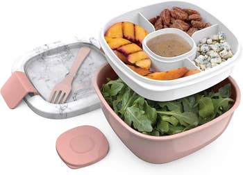 the two layer bentgo lunch box in pink, with salad in the bottom and toppings in the top container