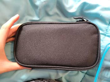 Person holding a achromatic  zippered pouch, perchance  utilized  for organizing oregon  storing tiny  items