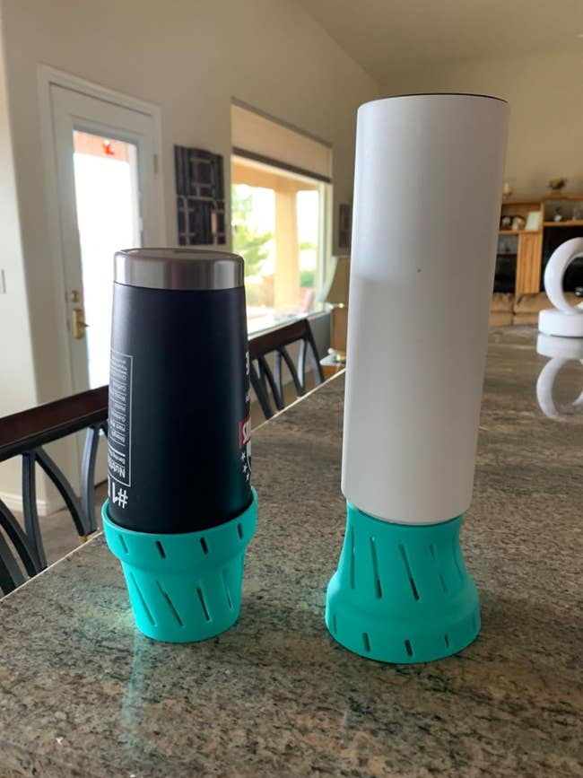 Two travel mugs with teal silicone holders on a kitchen counter