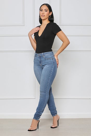 model wearing black v-neck bodysuit with blue jeans