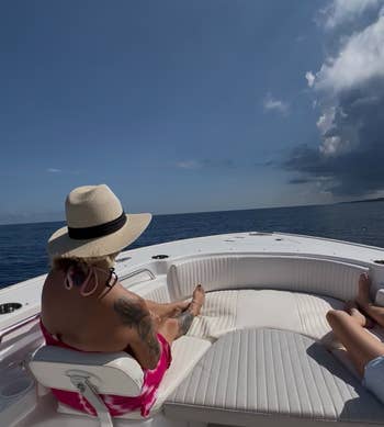 Person relaxing connected a boat, wearing a prima hat. Tattoo disposable connected arm. Clear entity and water successful the background. Perfect for abrogation buying context