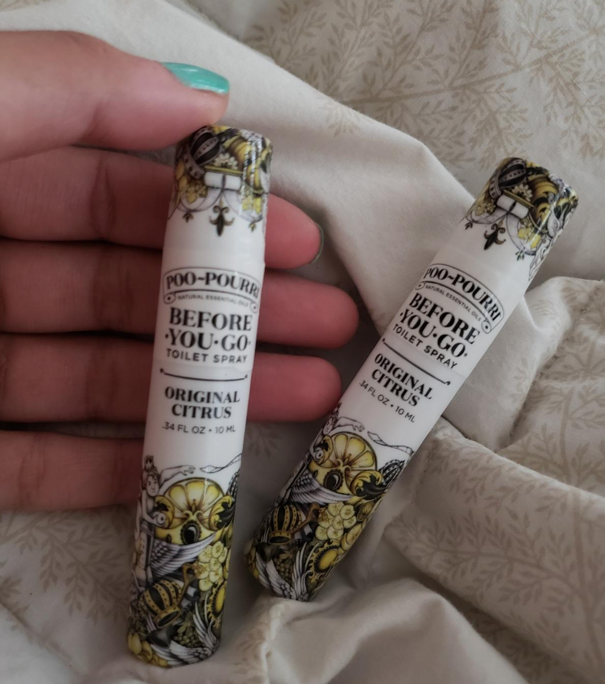 a reviewer holding two of the travel-size sprays