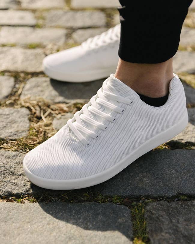 All-white sneakers on a model who's wearing black socks