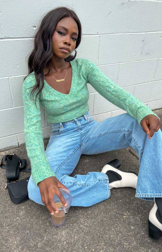 model in v-neck sweater and jeans