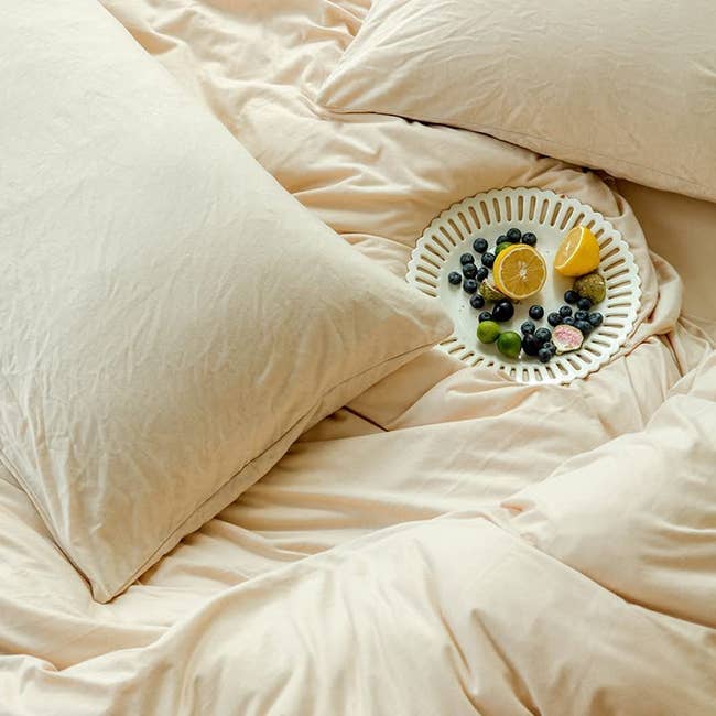 soft bed sheets with matching duvet cover and pillow cases with plate of fruit on the bed